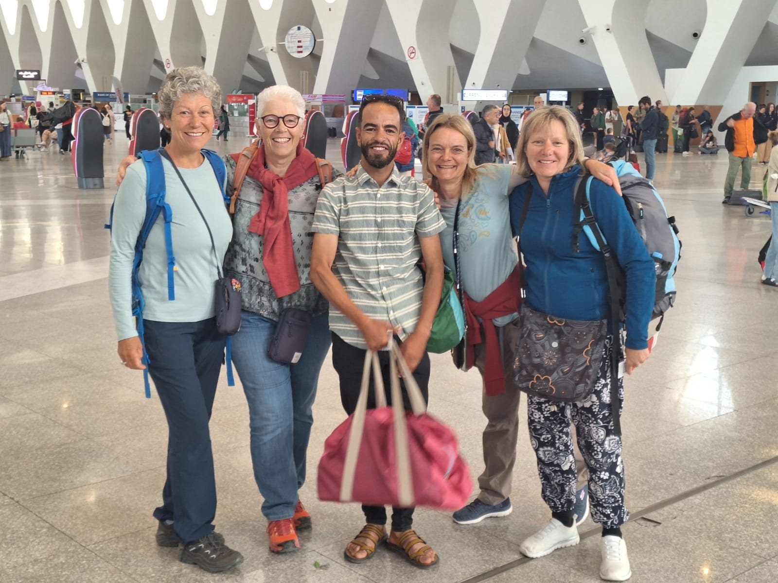 Amasir Voyage guide with four smiling travellers at Marrakech Menara airport
